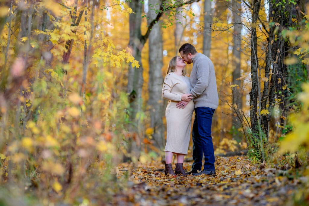 Couple walking through fall leaves at Geo Time Trail in Waterloo during golden hour engagement session