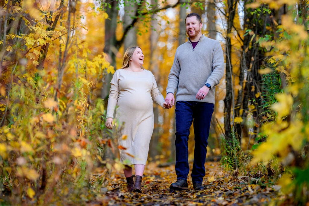 Couple walking through fall leaves at Geo Time Trail in Waterloo during golden hour engagement session