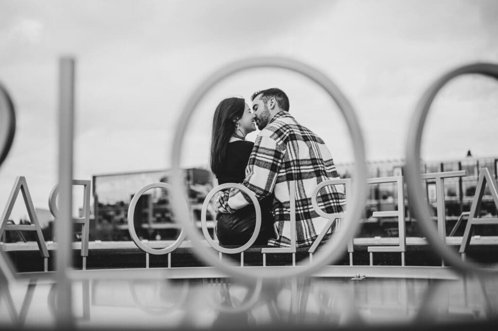 Engaged couple holding hands near historic bridge in Waterloo Park with colorful fall trees in the background